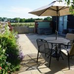 Private courtyard at Peanut Cottage with outdoor seating, parasol and hot tub in rural Norfolk.